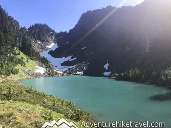 Milk Lake is a Hidden Gem in Olympic National Park Just a Short Hike Past Upper Lena Lake. If you have hiked all the way out to Upper Lena Lake and are still up for more hiking make sure you don't miss Milk Lake. This tiny glacier-fed lake is absolutely stunning with its turquoise blue waters. The vibrant colors of the lake in contrast with the lush green meadow filled with Avalanche Lillys is definitely an Olympic National Park must-see for those who are up for the challenge of backpacking for miles over rugged terrain.
