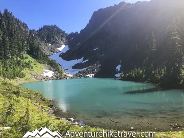 Milk Lake is a Hidden Gem in Olympic National Park Just a Short Hike Past Upper Lena Lake. If you have hiked all the way out to Upper Lena Lake and are still up for more hiking make sure you don't miss Milk Lake. This tiny glacier-fed lake is absolutely stunning with its turquoise blue waters. The vibrant colors of the lake in contrast with the lush green meadow filled with Avalanche Lillys is definitely an Olympic National Park must-see for those who are up for the challenge of backpacking for miles over rugged terrain.